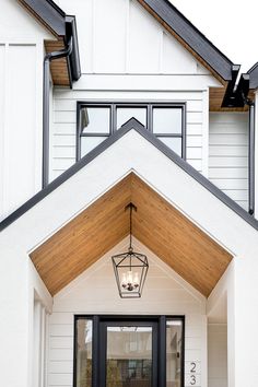 a white house with a black door and light fixture on the front entryway area