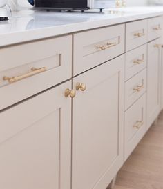 a white kitchen with gold handles and knobs on the cabinet doors is seen in this image