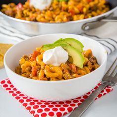 two bowls filled with chili, cheese and avocado on top of a table