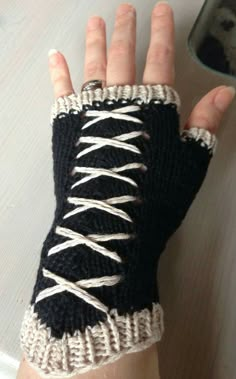 a person wearing a black and white knitted hand warmer with laces on it