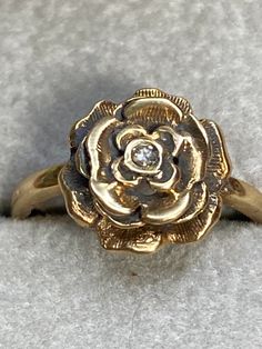 What an adorable ring! This dainty ring is 14K and hallmarked as such. It features intricate petals that for a flower with a 2 point center diamond. The setting measures 9mm in diameter. The ring is a size 3 1/2 and weighs in at 2.0 grams. First fine ring for you daughter? Pinky ring? Promise ring for the special person in your life? It's unique and gorgeous! Gold Thumb Rings, Ruby Solitaire Ring, Fine Ring, Mom Ring, Book Jewelry, Diamond Flower, Thumb Rings, Pinky Ring, Flower Ring