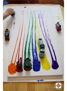 children's hands are painting different colored cars on a sheet of paper with watercolors