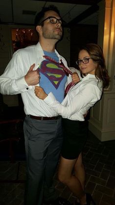 a man and woman are dressed up in business attire, one is holding a superman t - shirt