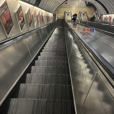 an escalator in a subway station with pictures on the wall