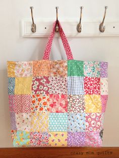 a multicolored patchwork bag hanging from a hook on a wall with the words easy mom quilts written below it