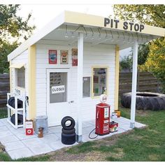 a small white building with a red gas pump next to it and a sign that says pit stop