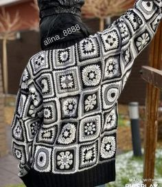 a woman wearing a black and white crochet jacket with her arms in the air