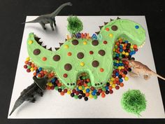 a dinosaur cake with sprinkles on it and other decorations around the cake