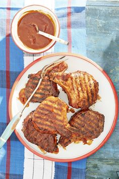 grilled meat on a plate next to a bowl of barbecue sauce and a spoon