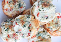 several small muffins with cheese and spinach on them sitting on a plate