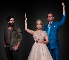 two men and a woman in formal wear posing for the camera with their hands up