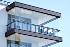 an apartment building with glass balconies and balcony railings on the top floor