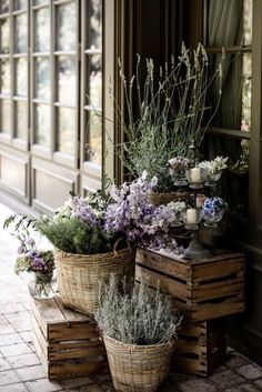 two baskets filled with flowers sitting on top of wooden crates next to a window sill