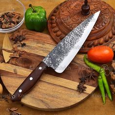 a large knife sitting on top of a wooden cutting board next to vegetables and spices