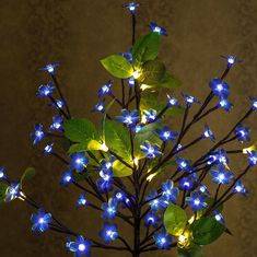 blue flowers with green leaves are lit up in the night time lightup arrangement on a table