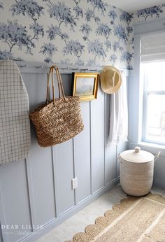 a basket and hat hanging on the wall in a room with blue floral wallpaper