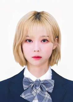 a young woman with blonde hair wearing a suit and bow tie in front of a white background