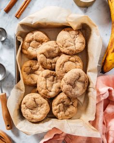 a bunch of cookies sitting in a paper bag next to some cinnamon sticks and bananas