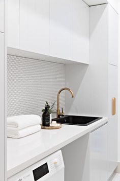 a kitchen with white cabinets and countertops has gold faucets on the sink