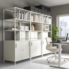 a room with a desk, chair and bookshelf next to a large window