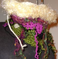 a crocheted hat is displayed on a mannequin's headdress