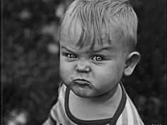 a black and white photo of a young boy with an angry look on his face