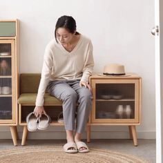 a woman sitting on a bench in front of a cabinet