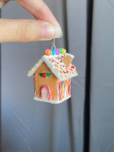 a hand holding a small gingerbread house keychain with candy and candies on it