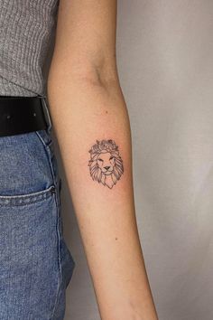 a woman's arm with a small tattoo of a lion on the left forearm