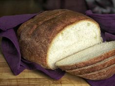 a loaf of bread sitting on top of a wooden cutting board next to a purple cloth