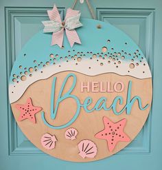 a wooden sign that says hello beach hanging on a blue door with seashells and starfish