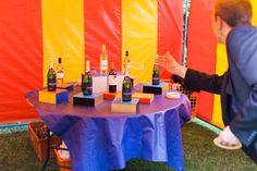 a man standing in front of a table with bottles of wine on top of it