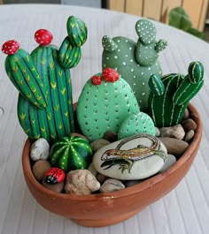 a bowl filled with lots of rocks and cacti on top of a table