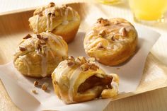 four pastries on a tray with orange juice in the background