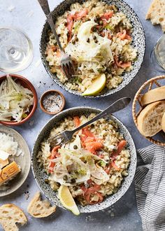 two bowls filled with rice and vegetables next to some bread on the side, along with wine glasses