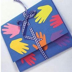 a blue card with colorful handprints on it and a ribbon tied to the front