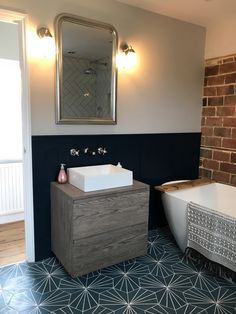 a bath room with a sink and a bath tub next to a brick wall in the background