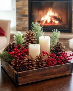 a wooden tray with candles and pine cones on it in front of a fire place