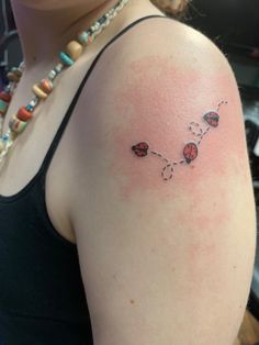 a ladybug tattoo on the left shoulder and right arm, with three ladybugs attached to it