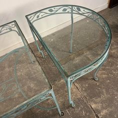 two glass tables sitting next to each other on the ground in front of a wall