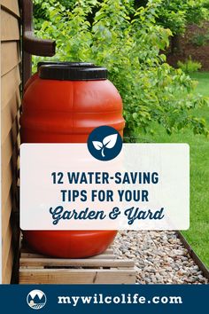 a large red barrel sitting on top of a wooden pallet next to a garden