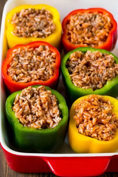 several peppers filled with rice in a red casserole dish