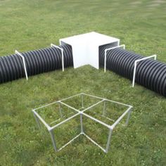 a group of black and white chairs sitting on top of a grass covered field next to pipes