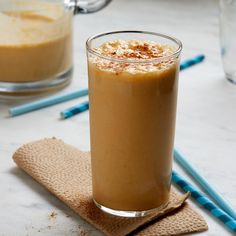 there is a drink on the table with two straws next to it and another cup in the background