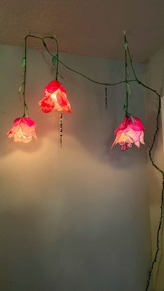 three pink flowers are hanging from the ceiling