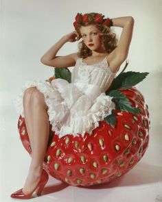 a woman sitting on top of a giant strawberry