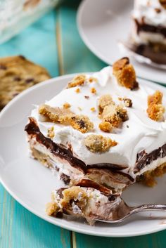 a piece of cake on a white plate with a fork and cookie in the background