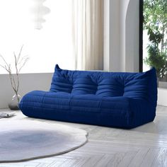 a blue futon sofa sitting on top of a white rug in a living room