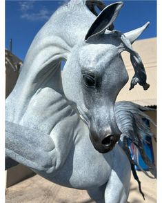 a statue of a white horse is shown in front of a building and blue sky