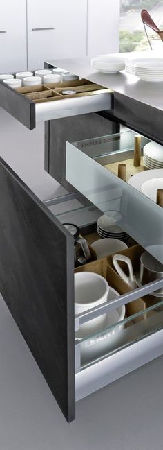 an open drawer in a kitchen filled with dishes